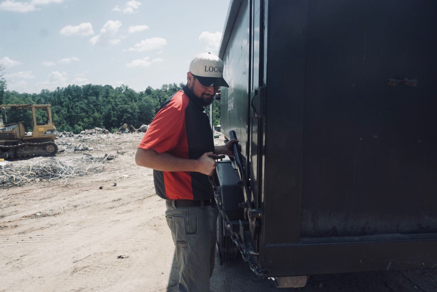 Muckpro operator securing chains on a loaded roll-off dumpster