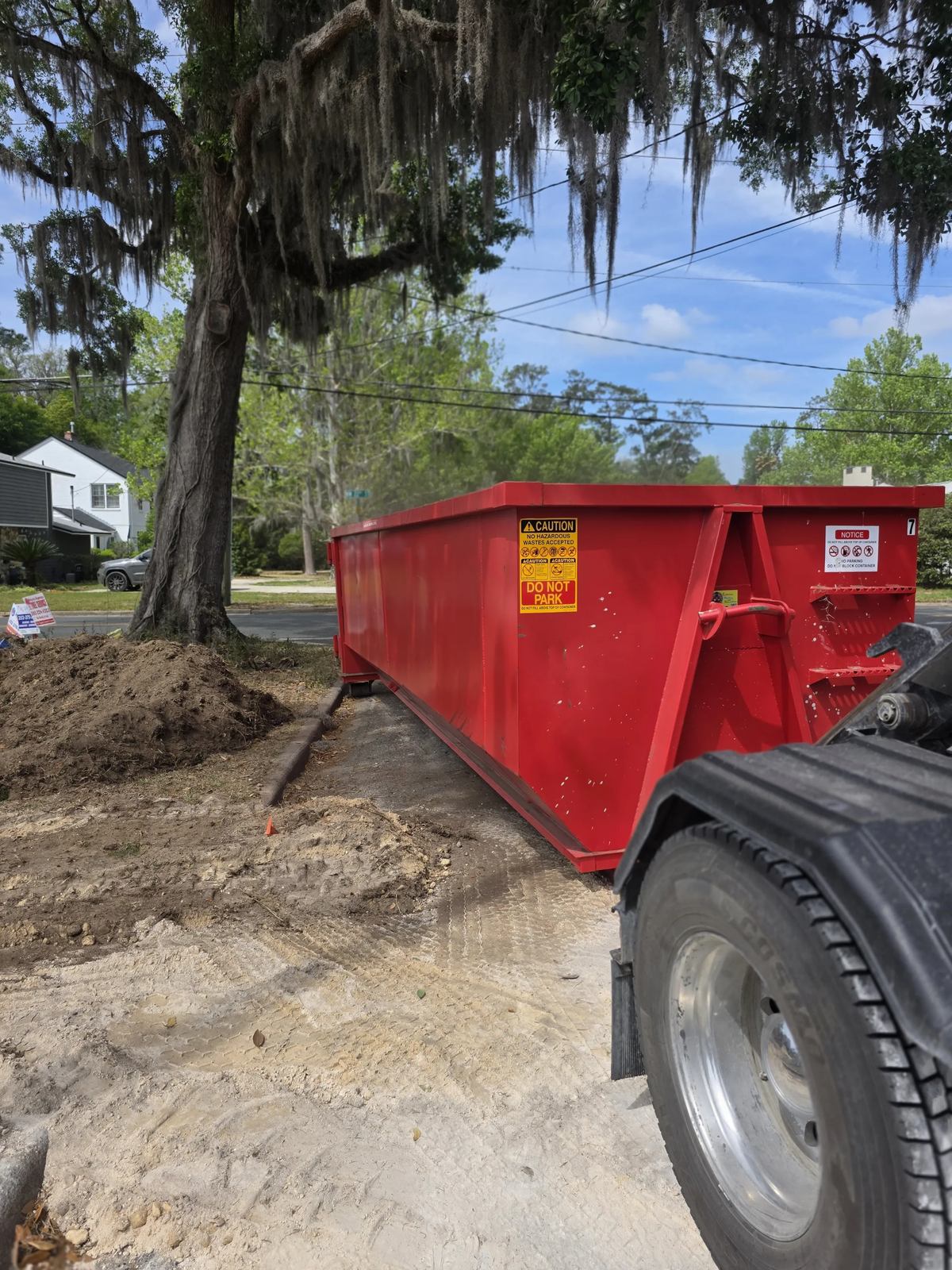 Muckpro roll-off dumpster placed curbside under live oaks in Gainesville FL