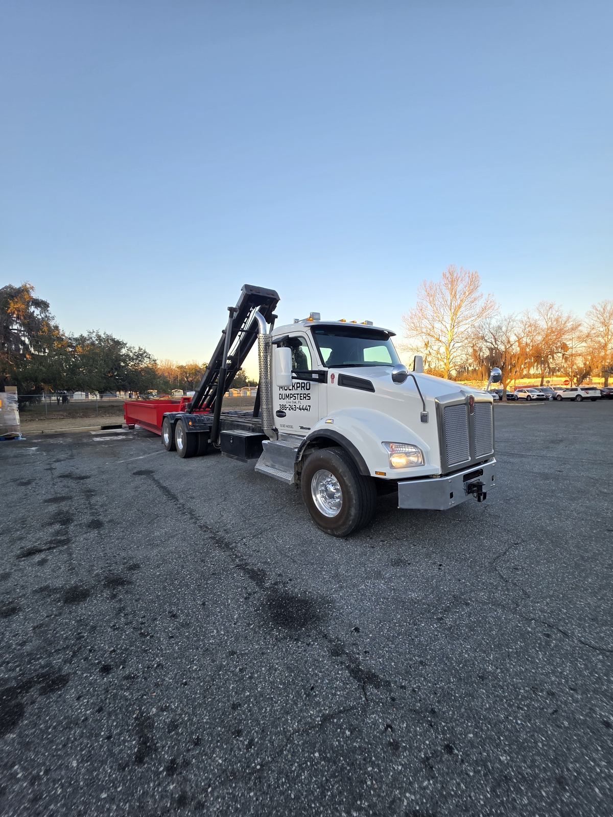 Muckpro roll-off truck dropping a dumpster in Lake City FL at dawn