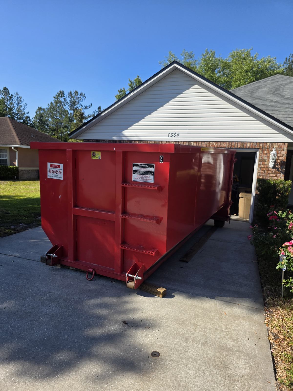 Muckpro roll-off dumpster set on protective boards on a Lake City FL driveway