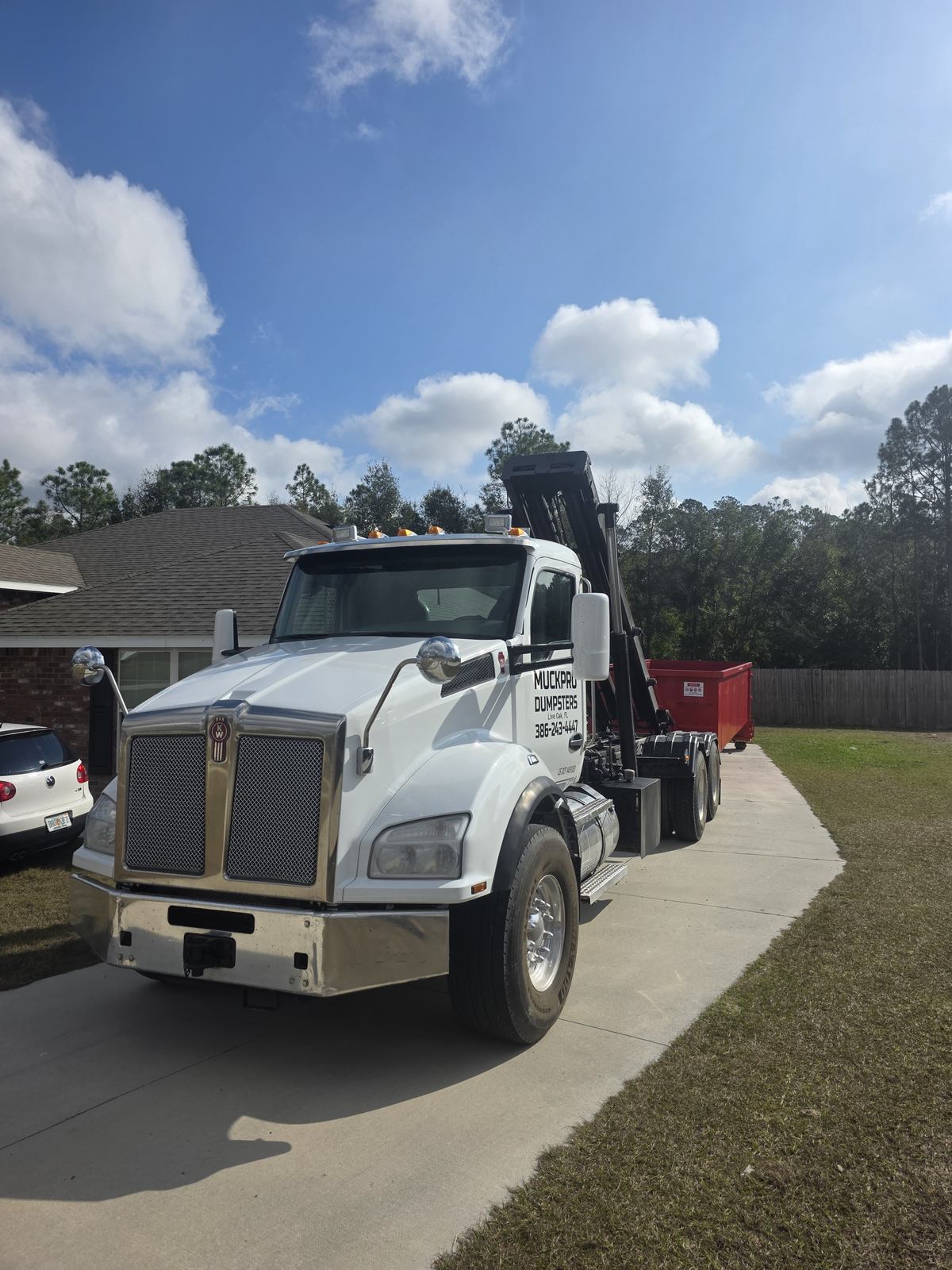 Muckpro roll-off truck delivering a dumpster to a Lake City FL home