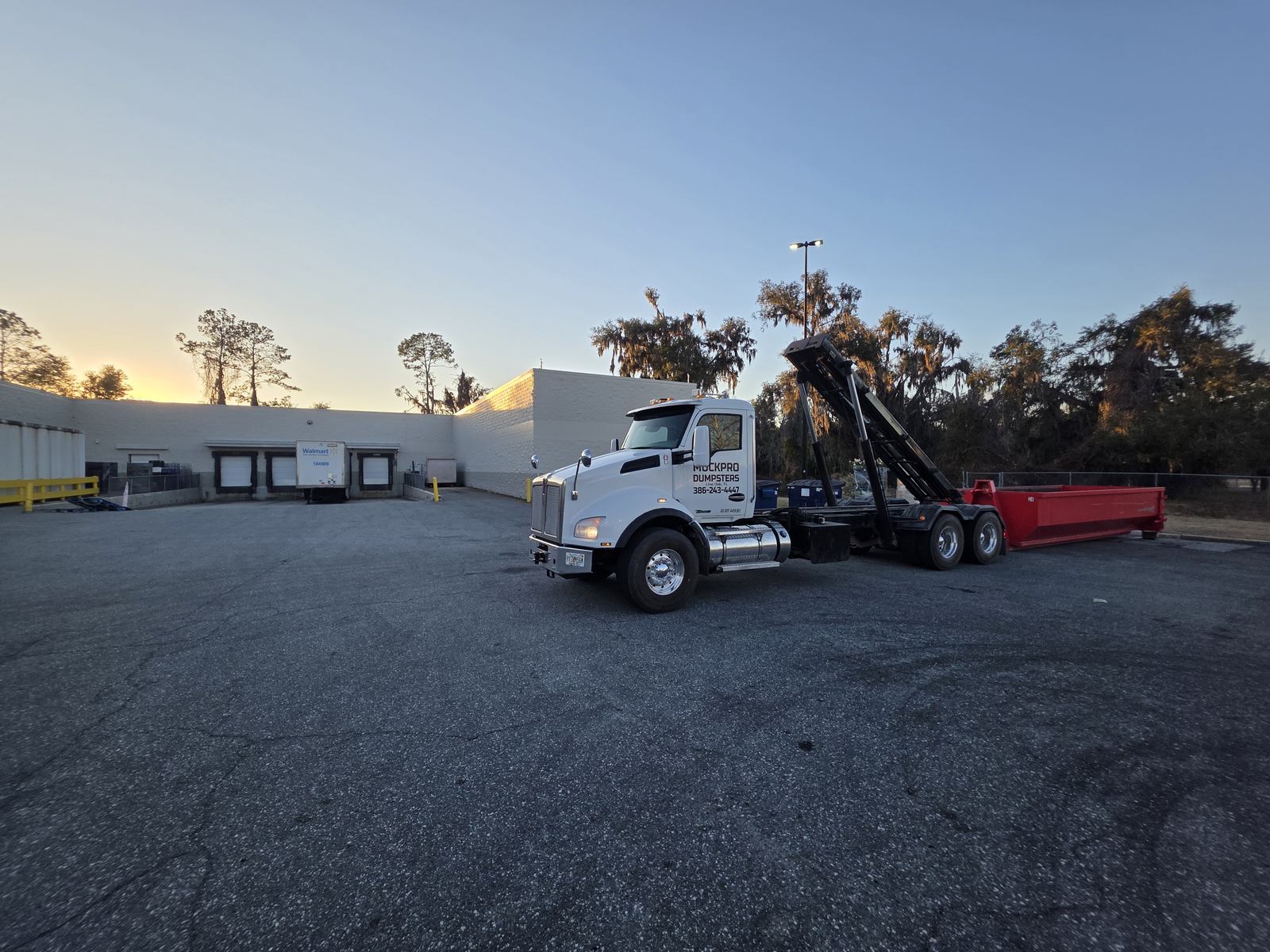 Muckpro roll-off truck on a sunrise commercial dumpster swap in Lake City FL