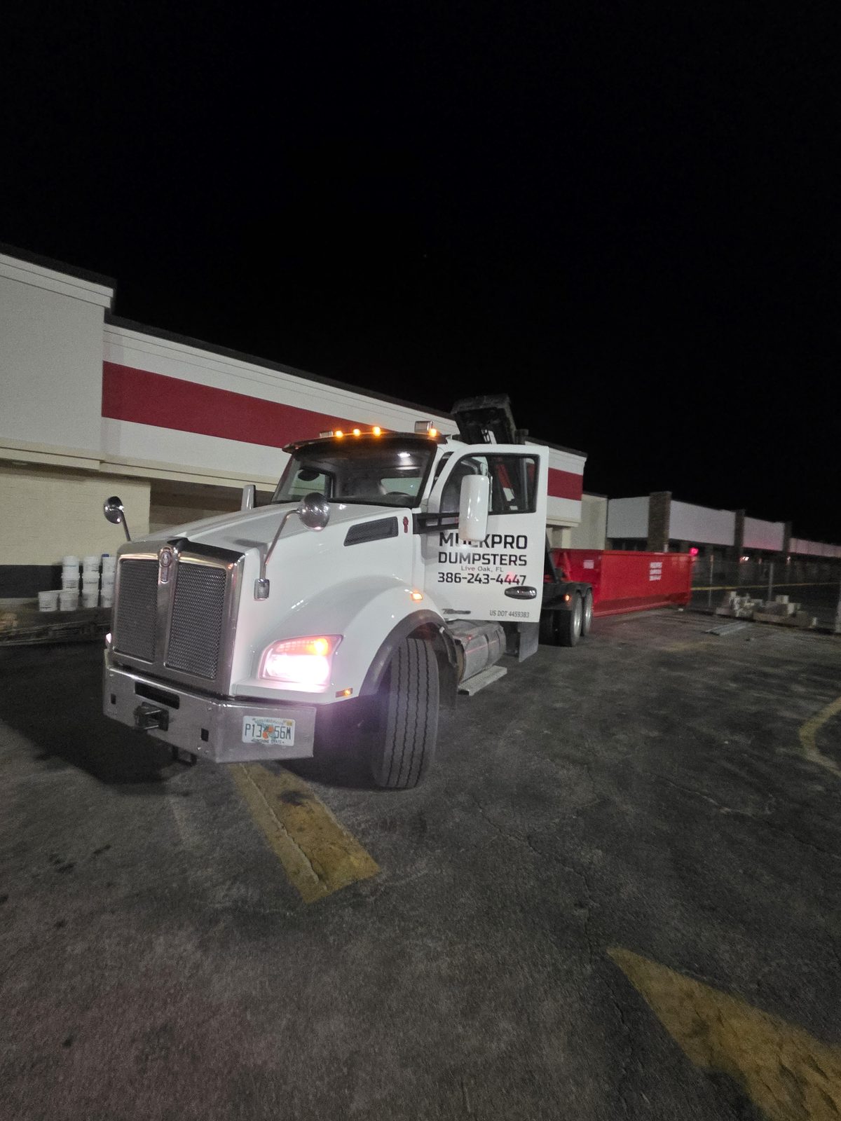 Muckpro roll-off truck on a night dumpster pull in Perry FL