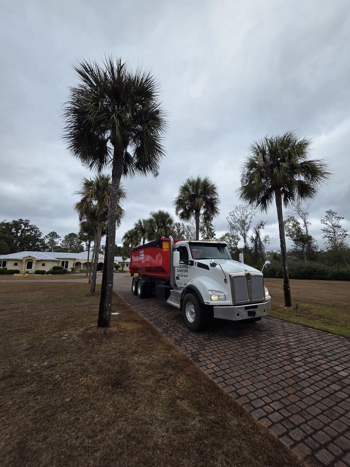 Muckpro roll-off dumpster delivery on a residential paver driveway in North Florida