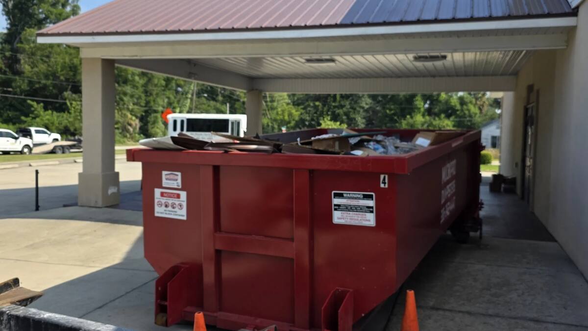 Muckpro dumpster placed under the portico for a church reroof off US 90 in Live Oak