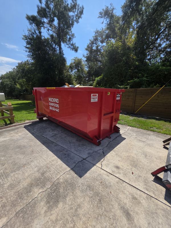 Muckpro dumpster placed on protective boards on a McAlpin FL driveway